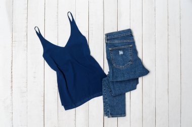 Giyim moda konsepti. Beyaz ahşap arka plan üzerinde mavi üst ve kot pantolon. Üstte görüntü