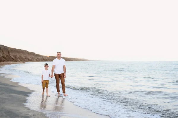Padre e hijo van de la mano a lo largo de la costa. Vacaciones familiares. Amistad — Foto de Stock