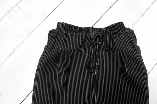 Concetto moda abbigliamento. Dettaglio pantaloni neri su fondo bianco in legno. Vista dall'alto — Foto Stock