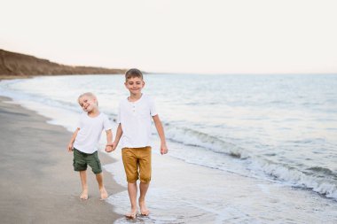 İki kardeş deniz kıyısında el ile yürürler. Aile tatili. Dostluk