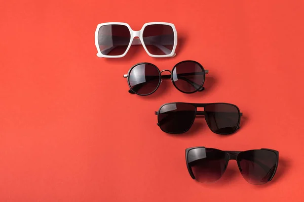 Four sun various glasses on live coral background. Travel concept