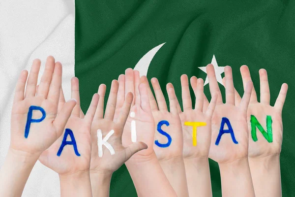 Inscription Pakistan on the children's hands against the background of a waving flag of the Pakistan