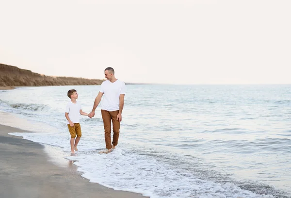 Padre e hijo van de la mano a lo largo de la costa. Vacaciones familiares. Amistad — Foto de Stock