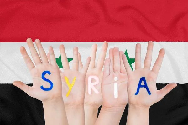 Inscripción Siria en las manos de los niños sobre el fondo de una bandera ondeante de Siria — Foto de Stock