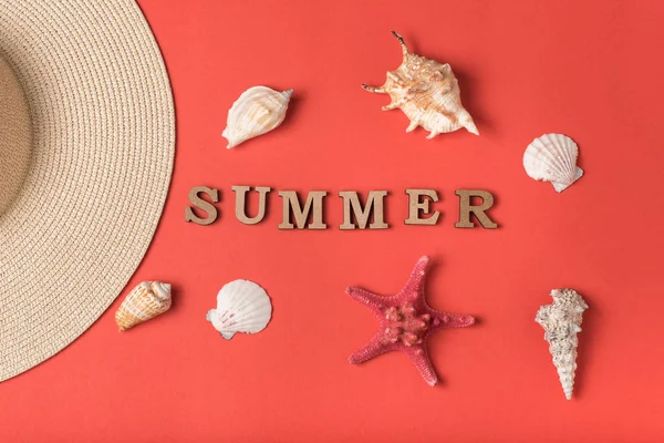 Word Summer from wooden letters. Seashells, starfish and part of a hat. Live coral background. Flat lay. Marine concept