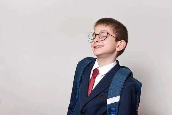 Retrato de un colegial curioso en traje, gafas y mochila. Concepto escolar. Fondo blanco . —  Fotos de Stock