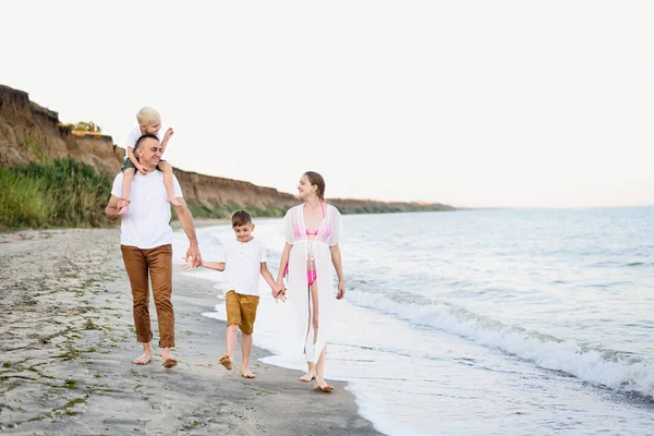 Familia de cuatro caminando por la orilla del mar. Padres y dos hijos. Familia amistosa feliz — Foto de Stock