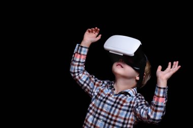 Sanal gerçeklik gözlüğü ile küçük sarışın çocuk bakar. Ekose gömlek. Siyah arka plan