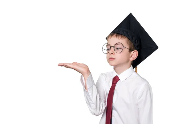 Garçon dans un chapeau académique carré et des lunettes tient sa paume vers le haut. Concept de l'école. Isoler — Photo