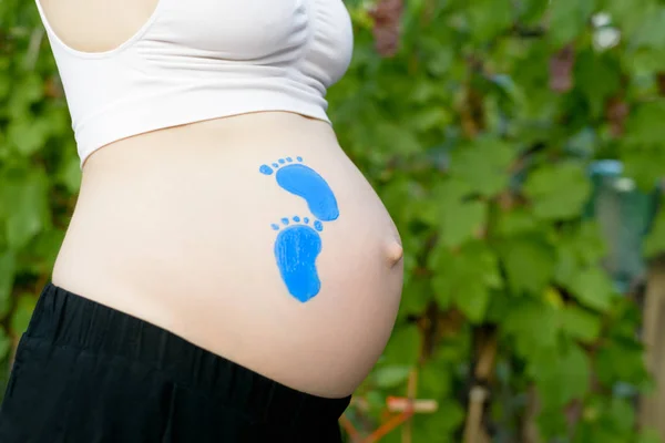 Pequeña huella azul dibujando en el vientre femenino embarazada. Concepto de embarazada. Primer plano — Foto de Stock