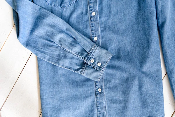 Ärm av blå jeans skjorta. Kläd koncept. Detaljer av skjorta på trä bakgrund. — Stockfoto