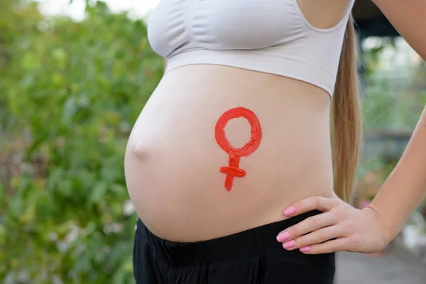 Símbolo femenino de género dibujado en una barriga femenina embarazada. Concepto de embarazada. Primer plano —  Fotos de Stock