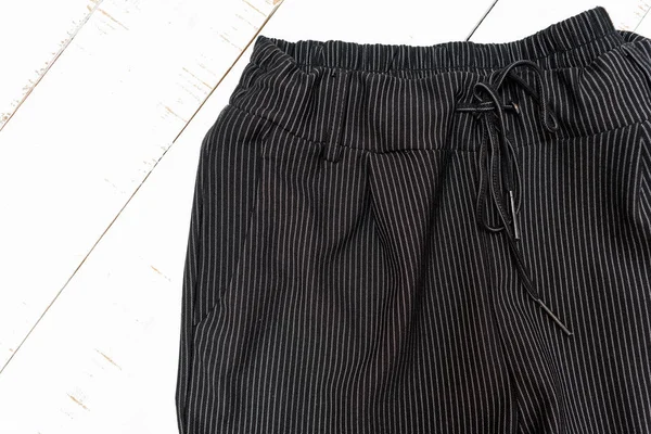 Koncepcja odzieży odzieżowych. Detale czarnych spodni na białym tle drewnianym. Widok z góry — Zdjęcie stockowe