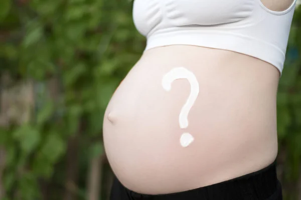 Un signo de interrogación dibujado en una barriga femenina embarazada. Concepto de embarazada. Primer plano — Foto de Stock