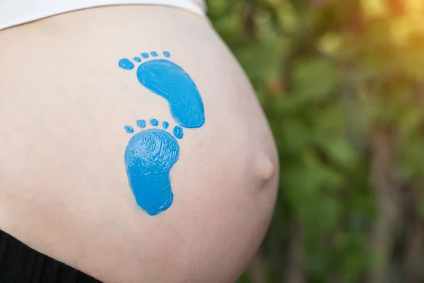Pequeña huella azul dibujando en el vientre femenino embarazada. Concepto de embarazada. Primer plano —  Fotos de Stock