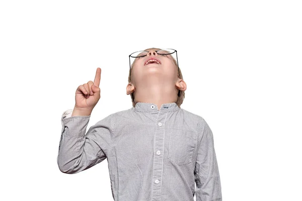 Retrato de um menino loiro bonito com óculos grandes. Ele olha para cima e aponta um dedo. Isolar — Fotografia de Stock