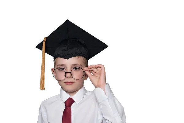 Boy in a square academic cap and white shirt correcting glasses. School concept. Isolate — Stock Photo, Image