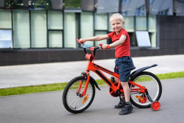 Çocuk bisikletinde sarışın çocuk. Kentsel arka plan