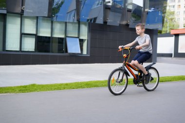 Okul çocuğu bisiklete biniyor. Yaz tatilleri. Kentsel arka plan