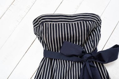 Giysi moda kavramı. Beyaz ahşap arka planda yay ile mavi çizgili elbise detay. Üst görünüm