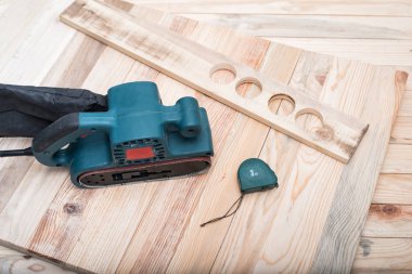 Elektrikli kemer zıpkın, ölçüm bandı ve iş parçası açık kahverengi ahşap bir masa üzerinde yatıyordu. Ahşap işleme, zıpzAma makinesi.