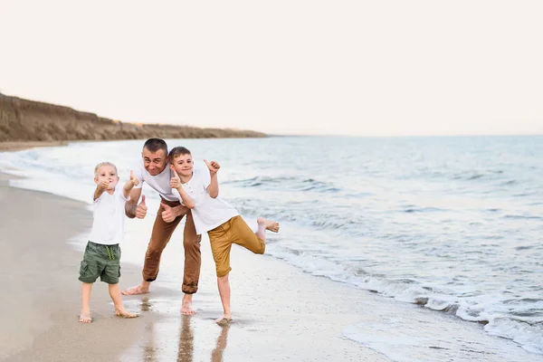 Padre y dos hijos muestran clase, costa del mar. Disfrutando de las vacaciones —  Fotos de Stock