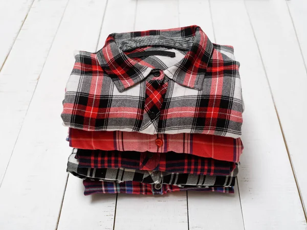 Stack of plaid shirts on a white wooden background. Clothing concept.