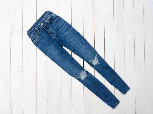 Синие рваные джинсы на белом деревянном фоне. Концепция одежды. Плоский лежал — стоковое фото