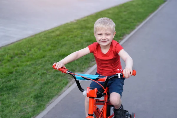 Portrait d'un beau garçon blond monté sur un vélo pour enfants. Contexte urbain — Photo