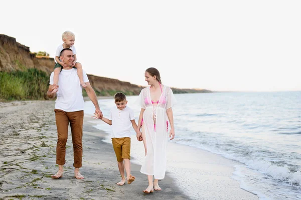 Familia de cuatro caminando por la orilla del mar. Padres y dos hijos. Familia amistosa feliz — Foto de Stock