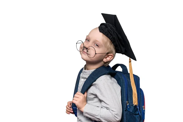 Portret zmęczonego blond chłopca w okularach, kapelusz akademicki i Torba szkolna. Koncepcja szkoły. Wyizolować — Zdjęcie stockowe