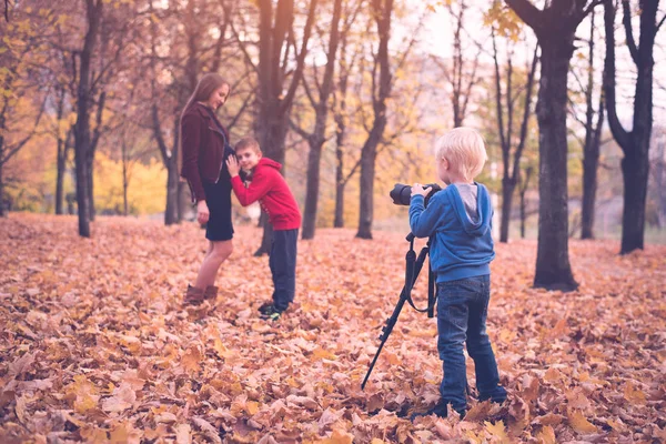 Mały blond chłopiec z dużym Lustrzanka na statywie. Fotografie ciężarnej matki i syna. Sesja zdjęciowa rodzinna — Zdjęcie stockowe