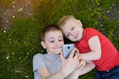 Çim üzerinde yatarken iki erkek bir smartphone üzerinde selfie yapmak. Üst görünüm