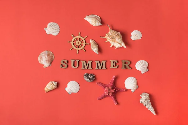 Word Summer from wooden letters. Seashells, starfish and steering wheel. Live coral background. Flat lay. Marine concept