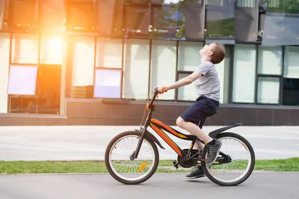 Schoolboy lovagol egy kerékpárt. Nyári szünidő. Városi háttér — Stock Fotó