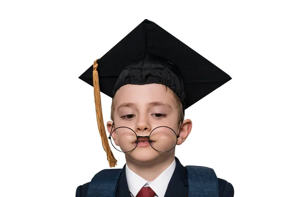 Divertido retrato de un colegial con sombrero académico y gafas grandes. Aislar. Concepto escolar —  Fotos de Stock