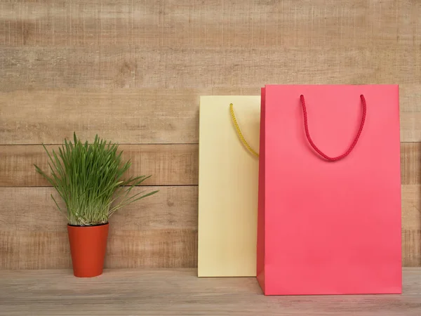 Twee boodschappentassen op een houten tafel. Groene kamerplant. Consumenten concept — Stockfoto