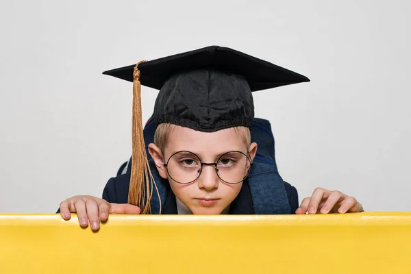 Portrait d'un écolier avec un chapeau académique et de grandes lunettes. Fond blanc. Concept scolaire — Photo