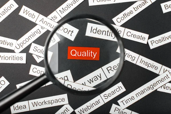 Magnifier glass over the red inscription quality cut out of paper. Surrounded by other inscriptions on a dark background. Word cloud concept. — Stock Photo, Image