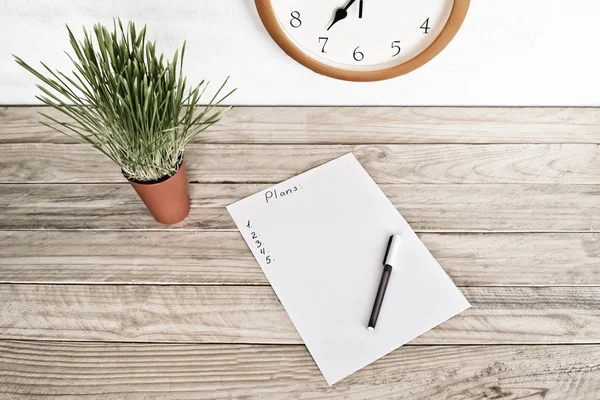 Foglio bianco di carta con un piano scritto e penna, pianta d'appartamento verde. Pianificazione aziendale — Foto Stock