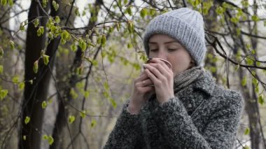 Kız bir çiçeği ağaç tarafından kahve içiyor. Islak kar