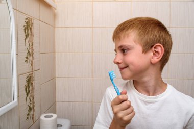 Elinde diş fırçası olan bir öğrenci, banyo. Sağlıklı alışkanlıklar