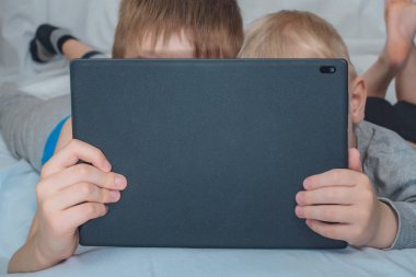 İki çocuk yatakta yatıyor ve tablete bakıyorlar. Boş zaman araçları