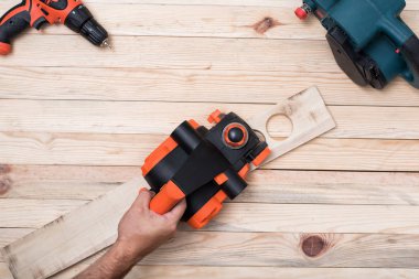 Erkek elinde elektrik planlayıcı. Açık kahverengi ahşap bir masa üzerinde iş parçası işleme. Doğrudan yukarıda