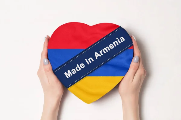 Inscripción Hecho en Armenia, la bandera de Armenia. Manos femeninas sosteniendo una caja en forma de corazón. Fondo blanco . — Foto de Stock