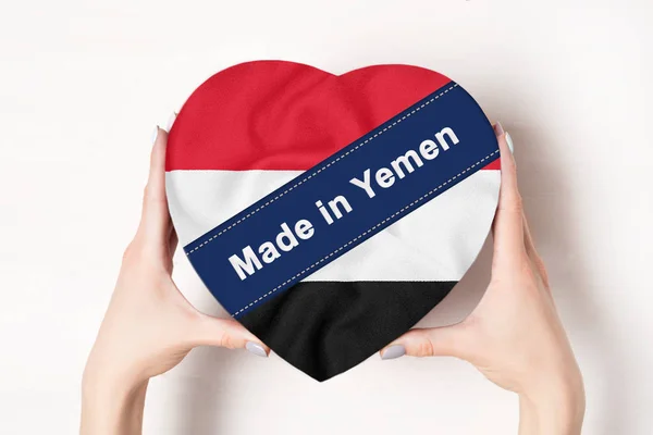 Inscripción Hecho en Yemen la bandera de Yemen. Manos femeninas sosteniendo una caja en forma de corazón. Fondo blanco . — Foto de Stock