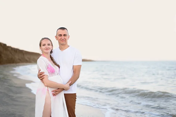 Casamento jovem casal na costa do mar. Marido abraça sua esposa grávida. Hora do pôr-do-sol — Fotografia de Stock