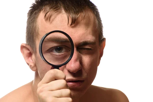 Große Augen. Ein Mann hält sich eine Lupe vor das Gesicht. Suche. weißer Hintergrund — Stockfoto