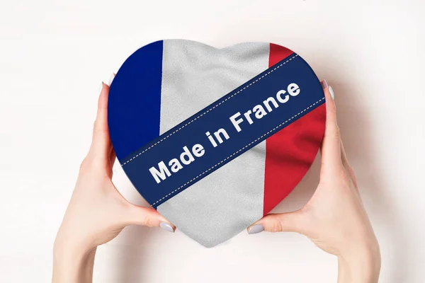 Inskripsi dibuat di Prancis, bendera Prancis. Tangan wanita memegang kotak berbentuk hati. Latar belakang putih. Tempat untuk teks — Stok Foto
