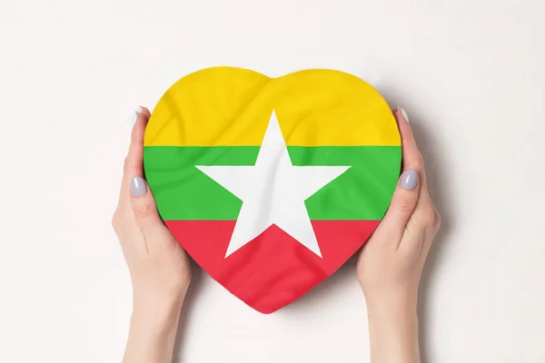Σημαία της Μιανμάρ σε ένα κουτί σε σχήμα καρδιάς σε γυναικεία χέρια. Λευκό φόντο — Φωτογραφία Αρχείου